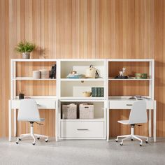 two white desks sitting next to each other in front of a wooden wall