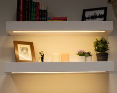 two shelves with candles, pictures and flowers on them are lit by the light from below