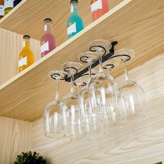 several wine glasses are hanging from a shelf