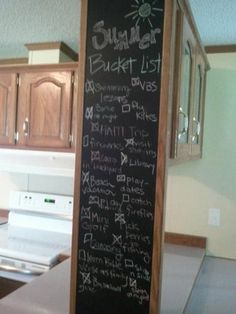 a blackboard with writing on it sitting in the middle of a kitchen next to an oven