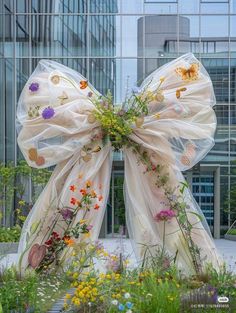 a large bow made out of sheer fabric with flowers on it in front of a building