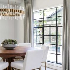 a dining room table with white chairs and a chandelier