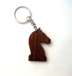 a wooden keychain with a horse head on it's side, sitting on a white surface