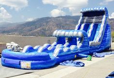 an inflatable water slide on the roof of a building with mountains in the background