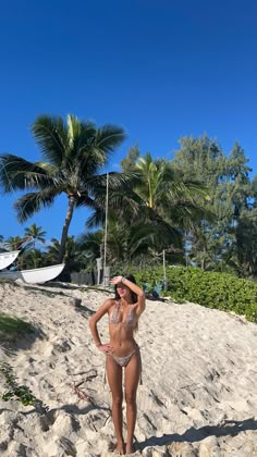 a woman standing on top of a sandy beach next to palm trees and umbrellas