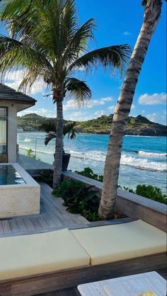 an outdoor hot tub next to the beach with palm trees and ocean in the background