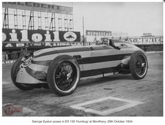 an old photo of a racing car in front of a baseball stadium with the scoreboard behind it