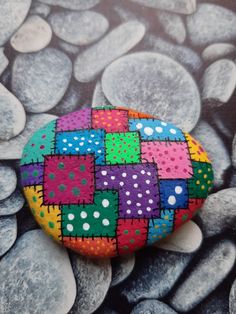 a colorful rock sitting on top of rocks covered in polka dot dots, with white dots