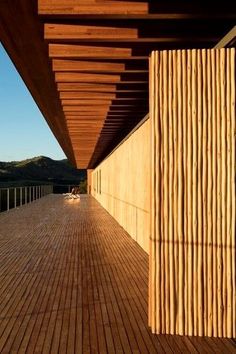 a wooden deck next to a building with mountains in the background