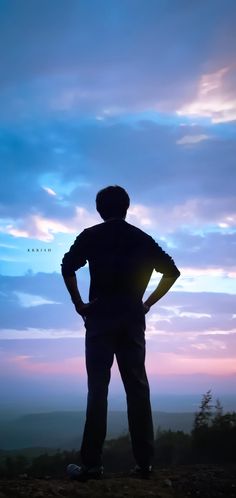 a man standing on top of a hill looking at the sky