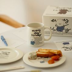 a table topped with two white plates and a cup filled with food next to a box