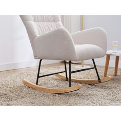 a white rocking chair sitting on top of a rug