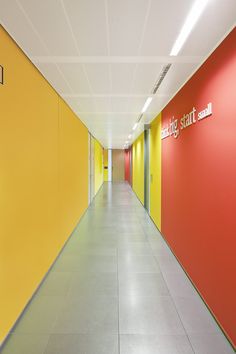 an empty hallway with bright yellow and red walls on both sides, leading to the exit