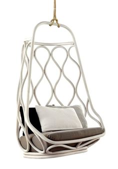 a white hanging chair with pillows on the back and seat cushion in front of it