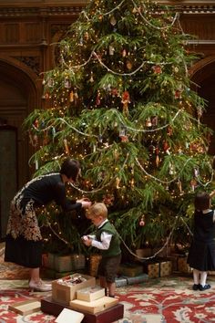 two young children are decorating a christmas tree