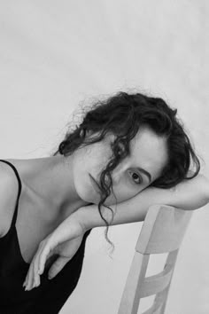 a black and white photo of a woman leaning on a chair