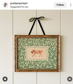 a painting hanging on the wall with a bow around it's neck and an image of a cow