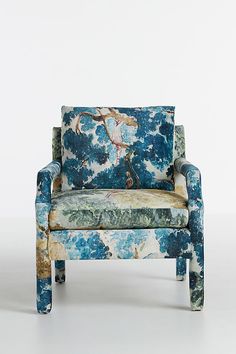 an upholstered chair with blue and green flowers on the back, against a white background