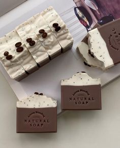 four soap bars with chocolate buttons on them sitting next to a box of soaps