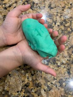 a hand holding a green substance in it's palm on a marble counter top