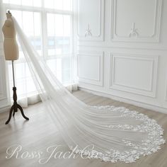 a white wedding veil is hanging on a mannequin in front of a window