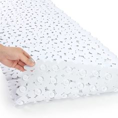 a person is placing buttons on the side of a white bed sheet that has holes in it