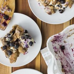 three plates with desserts on them sitting on a wooden table next to utensils