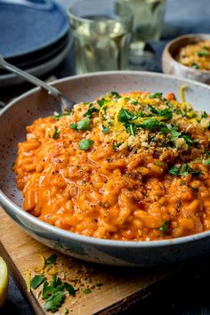 a bowl filled with macaroni and cheese on top of a wooden cutting board