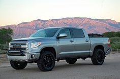 a silver truck parked in front of mountains