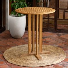 a wooden table sitting on top of a floor next to a potted plant