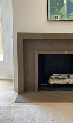 an empty fireplace with a painting on the wall