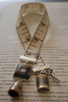 a pair of scissors, measuring tape and other items on top of an open book