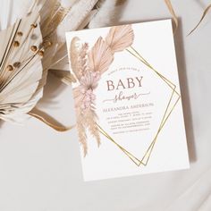 a baby shower with feathers and flowers on it's side, next to some feathers