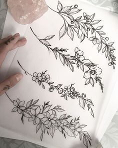 someone is drawing flowers and leaves on paper