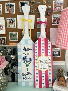 two wine bottle shaped tags on a desk with pictures and flowers in the back ground