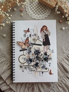 a notebook with an image of a woman and butterflies on the cover next to some flowers