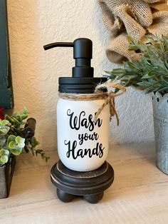 a soap dispenser sitting on top of a table next to a potted plant