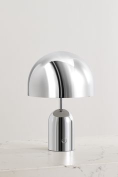 a chrome table lamp sitting on top of a white counter