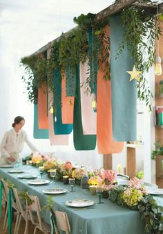 a long table is decorated with hanging plants and candles