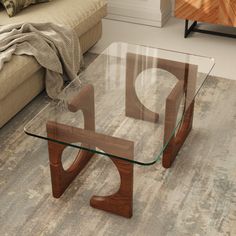 a glass coffee table with wooden legs on the floor in a modern living room area