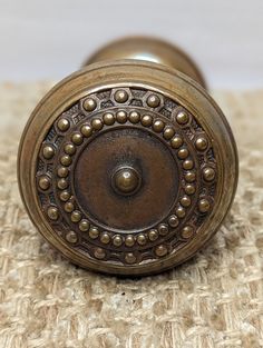 an antique brass door knob with beaded design on the outside and inside, sitting on a carpeted surface