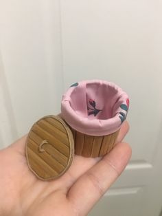 a hand holding a small toy cupcake in it's palm