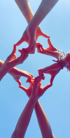 four hands reaching up into the air to reach something in the sky with their fingers