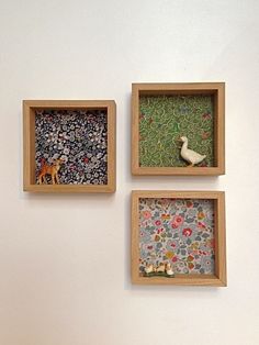 three small wooden boxes with animals and flowers in them on the side of a wall