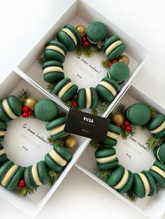 three boxes filled with green and gold decorated doughnuts in the shape of wreaths