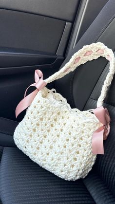 a crocheted purse sitting in the back seat of a car with a pink bow