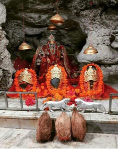 there is a statue in the cave with decorations on it and three bells hanging from the ceiling