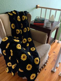 a chair with a blanket that has sunflowers on it