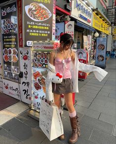 a woman is standing on the sidewalk with shopping bags