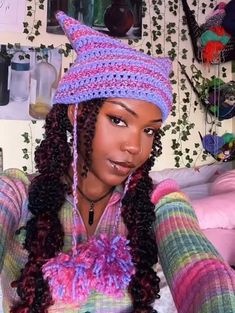 a woman wearing a crochet hat with braids on her head and purple hair